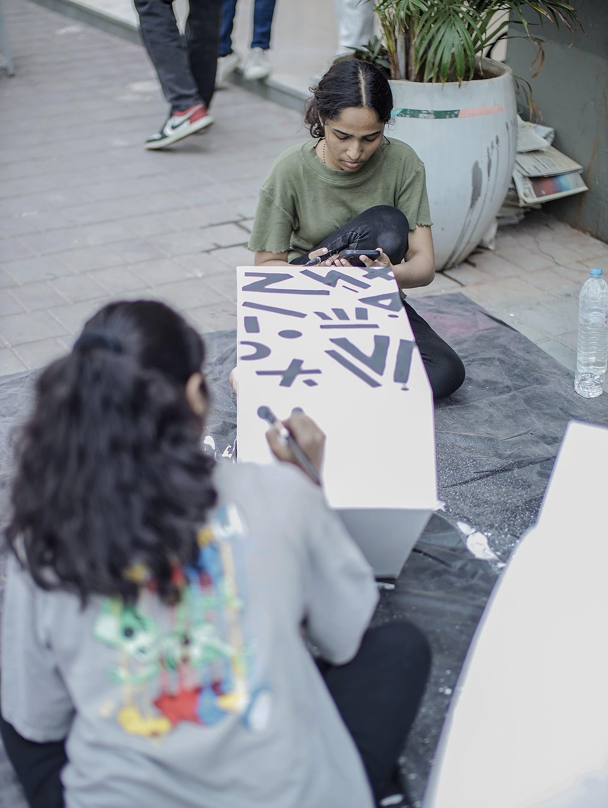 Students painting posters on the studio floor