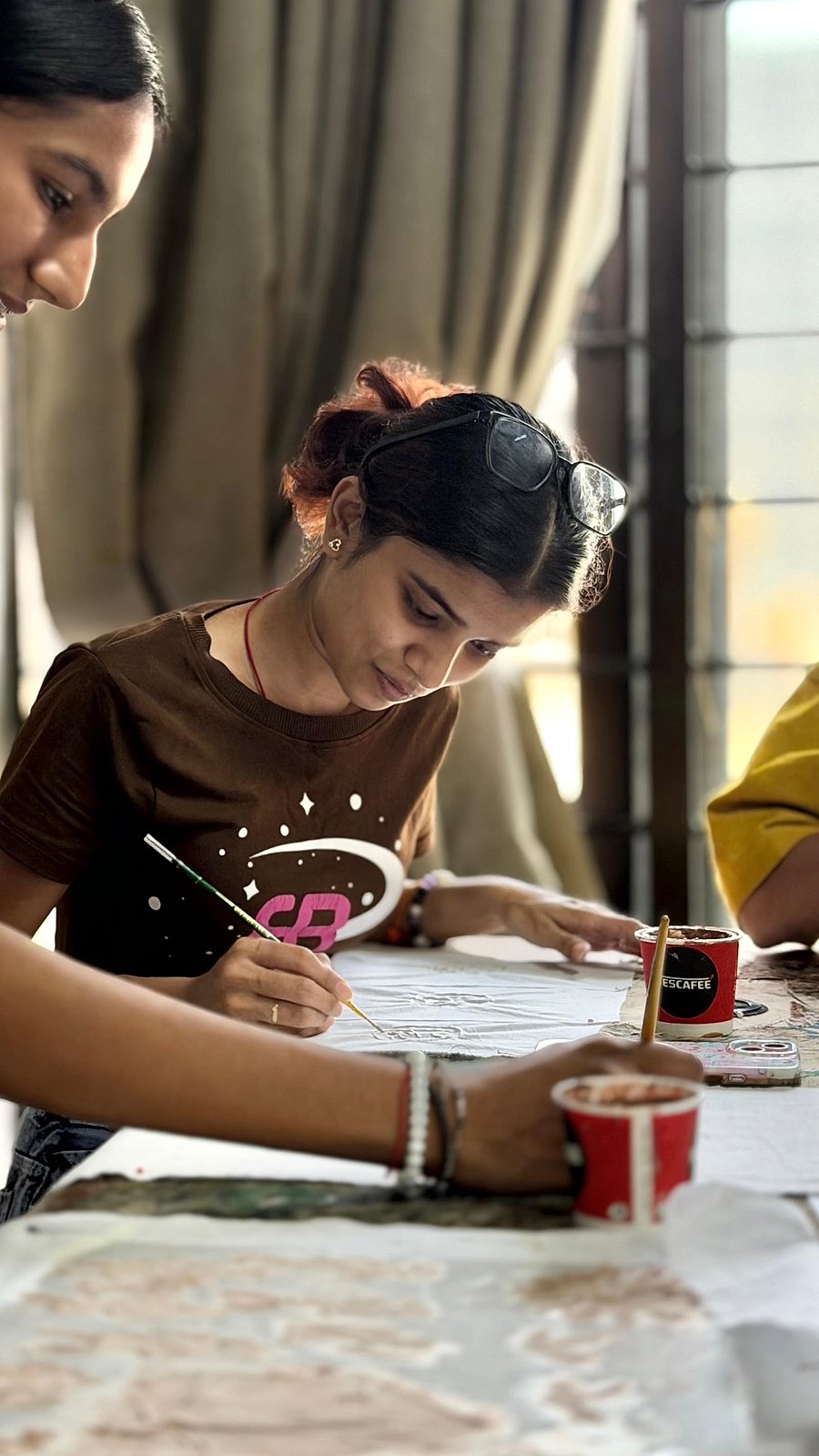 Student painting with chai on the table