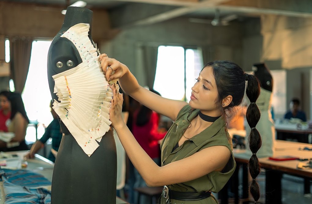 Student draping and pinning fabric on a dress form