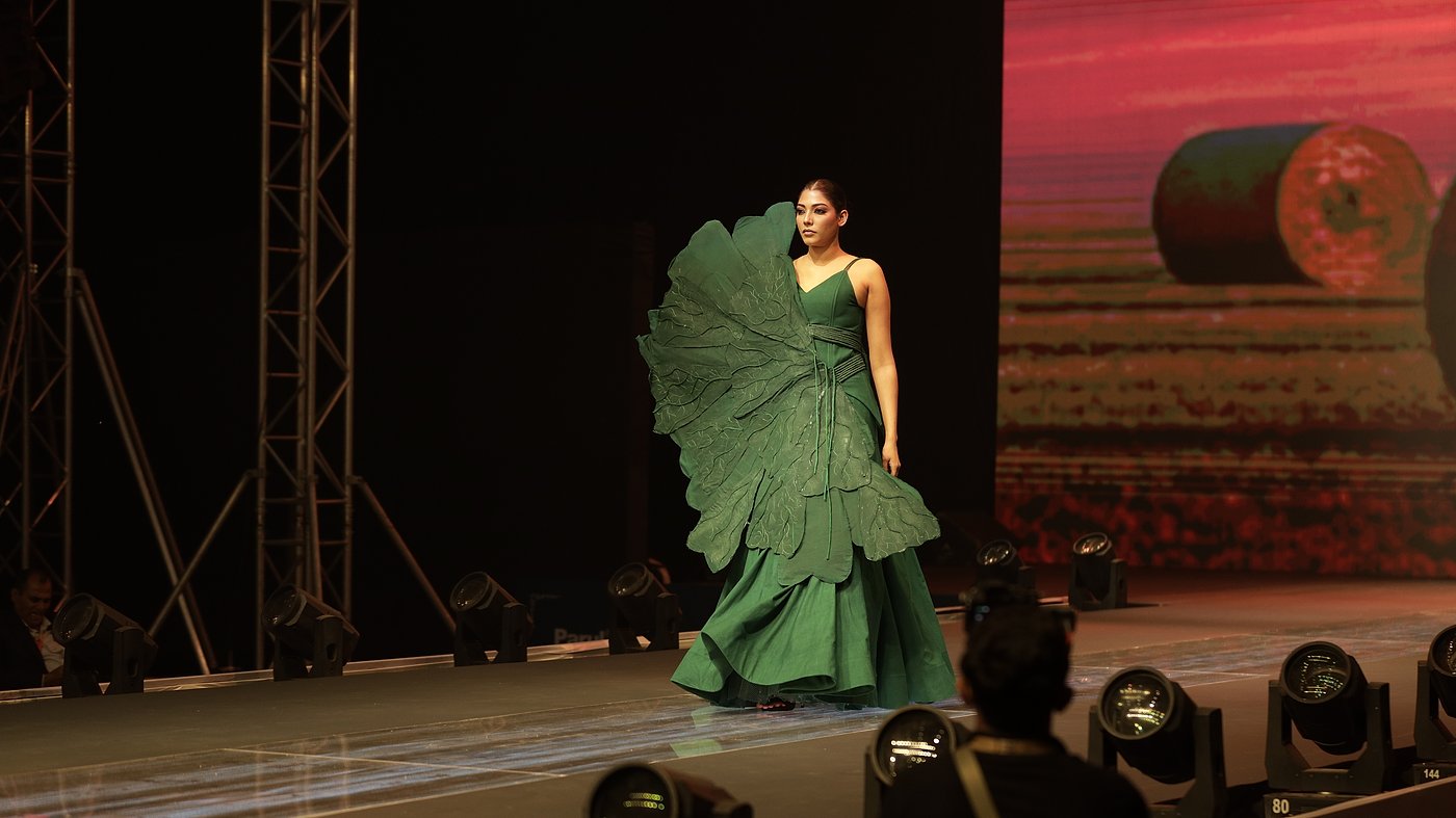 Student in a green sculptural gown on the runway