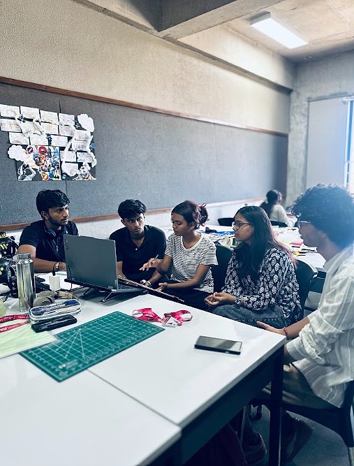 Students working around a laptop at a studio table